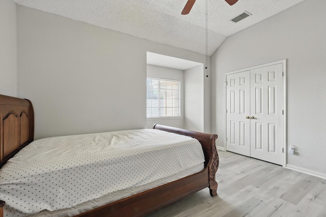 bedroom with light wood finished floors, vaulted ceiling, a closet, baseboards, and ceiling fan