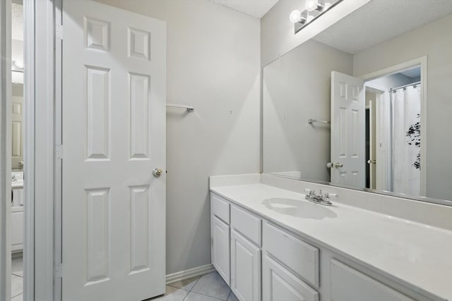 bathroom featuring vanity, tile patterned flooring, a textured ceiling, and baseboards