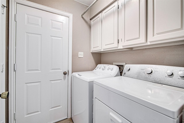 laundry room with washer and dryer, cabinet space, and a textured wall