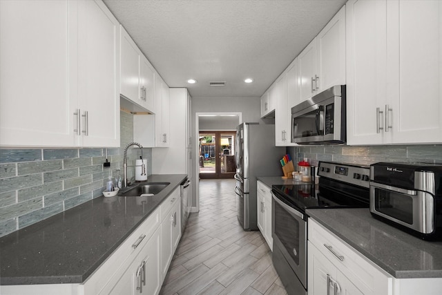 4677 Bracken Dr, Fort Worth, TX 76137 - kitchen featuring appliances with stainless steel finishes, a sink, decorative backsplash, recessed lighting, and white cabinets