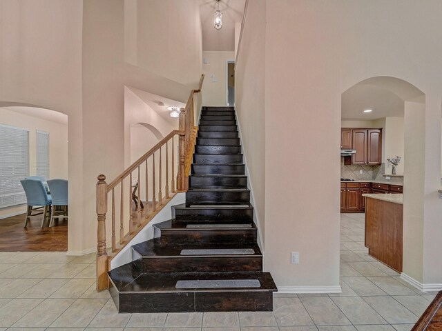 8431 Firewheel Ln, Frisco, TX 75036 - stairway with tile patterned flooring, a high ceiling, arched walkways, and baseboards
