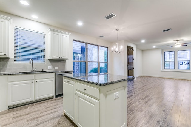 kitchen with stainless steel dishwasher, a sink, a kitchen island, light wood finished floors, and open floor plan