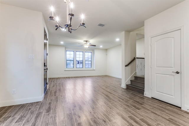 unfurnished living room featuring wood finished floors, a chandelier, stairs, baseboards, and recessed lighting