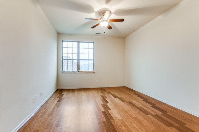 spare room featuring light wood-type flooring, a ceiling fan, and baseboards