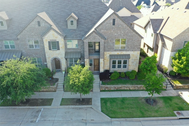 view of front of home with stone siding, a front lawn, and brick siding