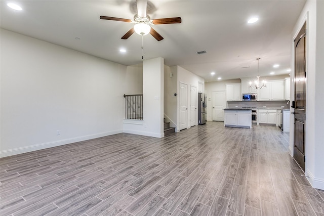 unfurnished living room with a chandelier, light wood-style flooring, baseboards, a ceiling fan, and recessed lighting