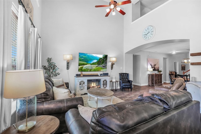 2812 Arabian Ln, Celina, TX 75009 - living area featuring arched walkways, a towering ceiling, a ceiling fan, wood finished floors, and baseboards