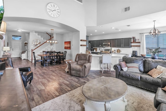 2812 Arabian Ln, Celina, TX 75009 - living room with a chandelier, stairway, wood finished floors, arched walkways, and a towering ceiling