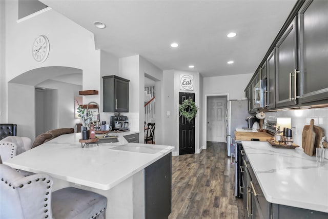 2812 Arabian Ln, Celina, TX 75009 - kitchen featuring stainless steel microwave, a peninsula, range, a breakfast bar, and dark wood-style floors