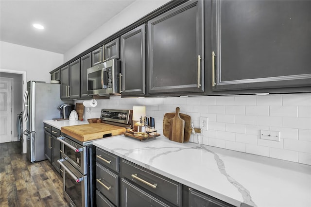 2812 Arabian Ln, Celina, TX 75009 - kitchen featuring appliances with stainless steel finishes, backsplash, dark wood-type flooring, light stone counters, and dark cabinets