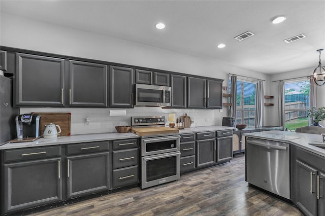 2812 Arabian Ln, Celina, TX 75009 - kitchen featuring stainless steel appliances, light countertops, backsplash, dark wood-style flooring, and pendant lighting