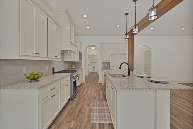 164 Vz County Road 2433, Canton, TX 75103 - kitchen with stainless steel stove, a sink, arched walkways, light wood-type flooring, and backsplash
