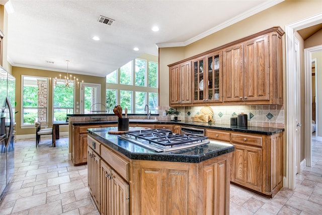 1900 Pembroke Ln, Mckinney, TX 75072 - kitchen featuring stainless steel appliances, stone tile floors, decorative backsplash, brown cabinets, and crown molding