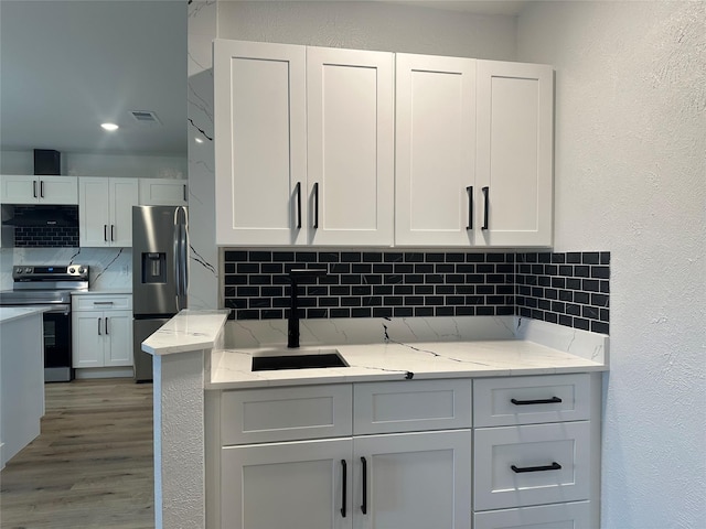 7501 Echo Hill Dr, Watauga, TX 76148 - kitchen with appliances with stainless steel finishes, decorative backsplash, a sink, white cabinets, and a textured wall