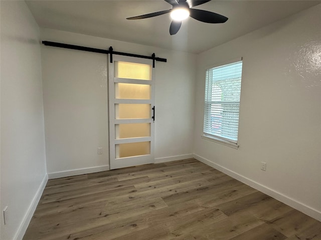 7501 Echo Hill Dr, Watauga, TX 76148 - spare room featuring a barn door, ceiling fan, and wood finished floors