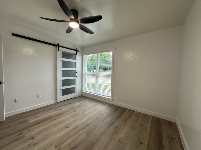 7501 Echo Hill Dr, Watauga, TX 76148 - empty room with a barn door, baseboards, wood finished floors, and a ceiling fan