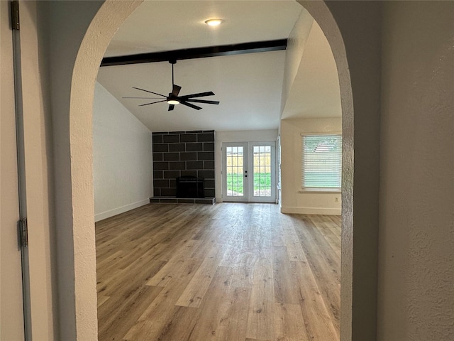 7501 Echo Hill Dr, Watauga, TX 76148 - unfurnished living room with ceiling fan, arched walkways, light wood-style floors, baseboards, and a textured wall