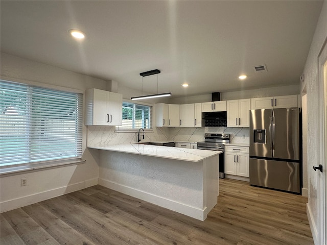 7501 Echo Hill Dr, Watauga, TX 76148 - kitchen featuring appliances with stainless steel finishes, white cabinetry, a peninsula, tasteful backsplash, and recessed lighting