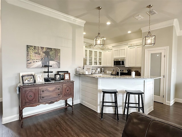 7415 Morning Glory Rd, Abilene, TX 79602 - kitchen featuring stainless steel microwave, crown molding, tasteful backsplash, white cabinetry, and dark wood-style flooring