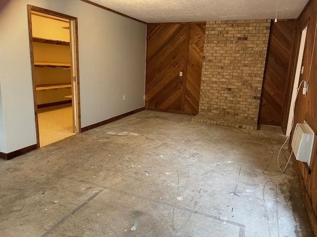 1942 S Lakeshore, Rockwall, TX 75087 - unfurnished bedroom with wood walls, a spacious closet, a textured ceiling, baseboards, and a closet