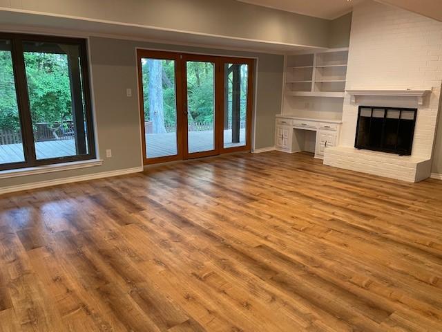 1942 S Lakeshore, Rockwall, TX 75087 - unfurnished living room featuring healthy amount of natural light, wood finished floors, baseboards, and a fireplace