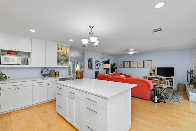 kitchen with white microwave, open shelves, open floor plan, light wood finished floors, and recessed lighting