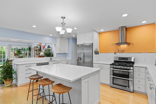 kitchen with stainless steel appliances, wall chimney range hood, backsplash, a center island, and a kitchen bar