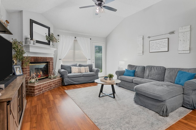 living room with lofted ceiling, wood finished floors, ceiling fan, and a fireplace