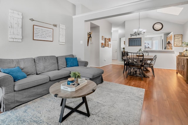 living area featuring vaulted ceiling, a chandelier, wood finished floors, and a skylight