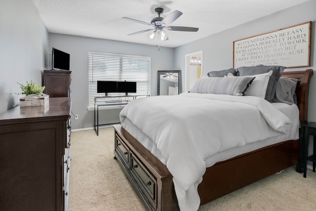 bedroom with light carpet, a ceiling fan, ensuite bath, and a textured ceiling