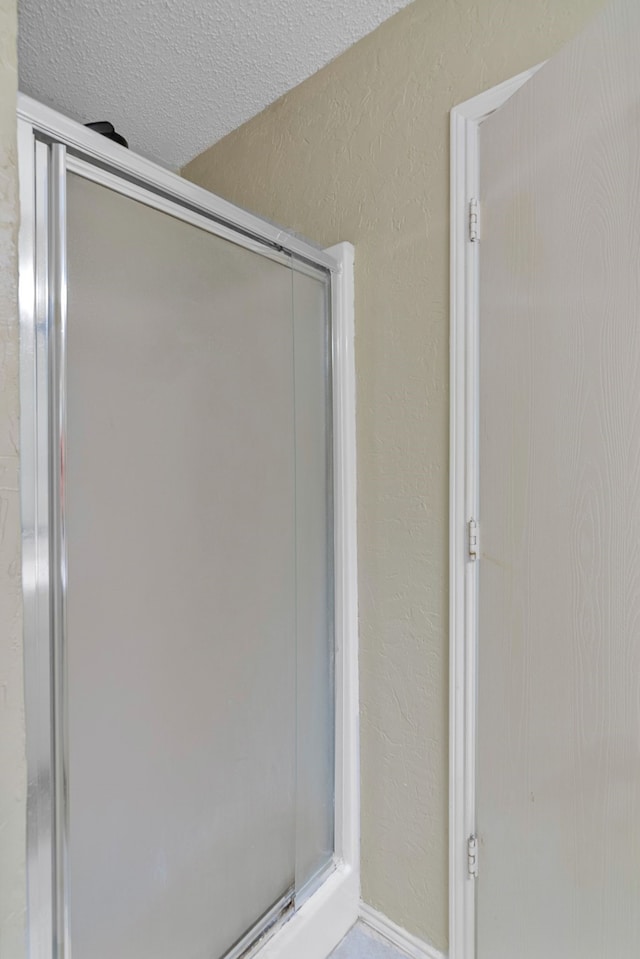 bathroom with a stall shower and a textured ceiling