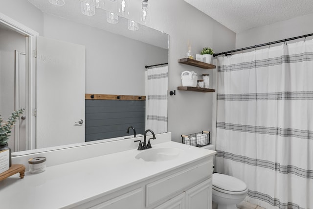 bathroom with a textured ceiling, toilet, vanity, and curtained shower