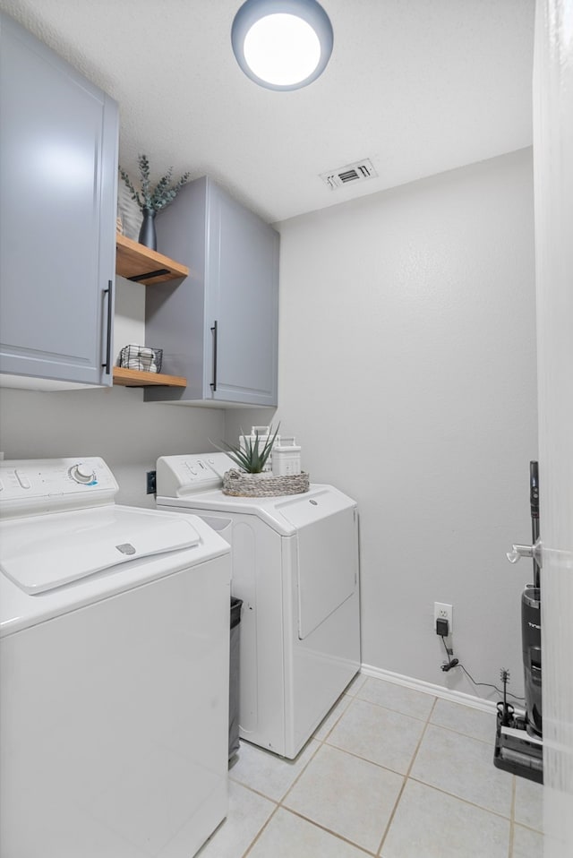 clothes washing area featuring cabinet space, washer and dryer, and light tile patterned flooring