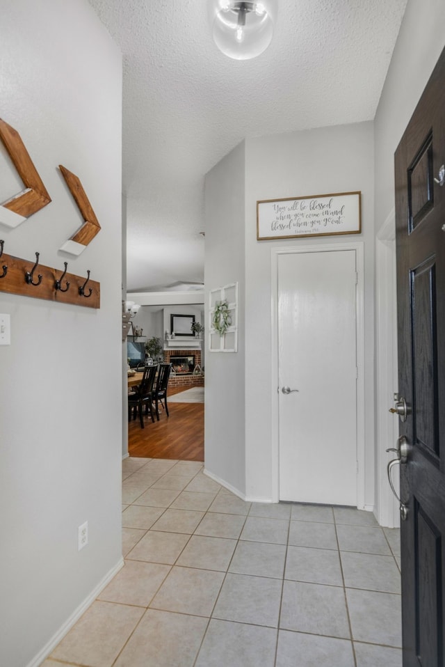 foyer featuring light tile patterned flooring, a textured ceiling, and baseboards
