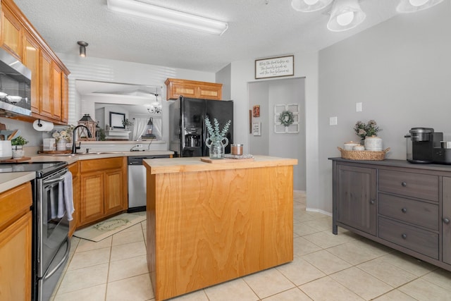 kitchen featuring stainless steel appliances, a center island, a sink, a textured ceiling, and light tile patterned floors