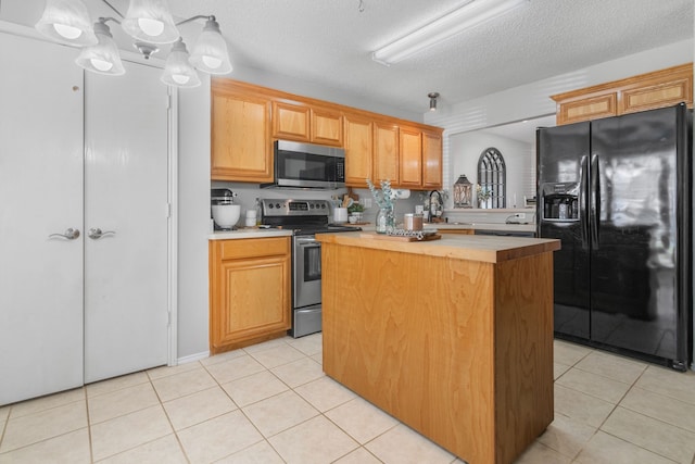 kitchen with stainless steel appliances, light countertops, light tile patterned floors, and a textured ceiling