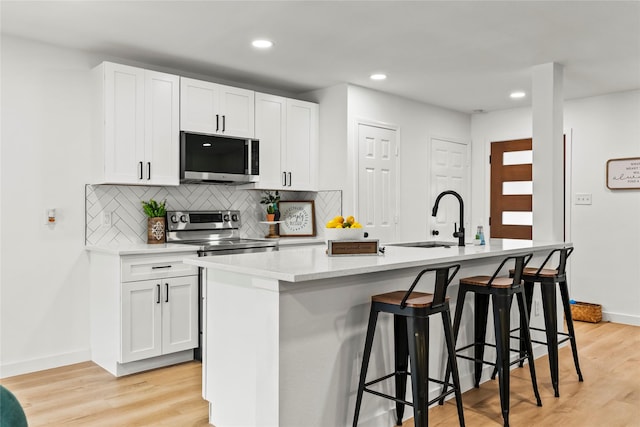 1303 Johns Dr, Euless, TX 76039 - kitchen featuring appliances with stainless steel finishes, a sink, an island with sink, tasteful backsplash, and recessed lighting