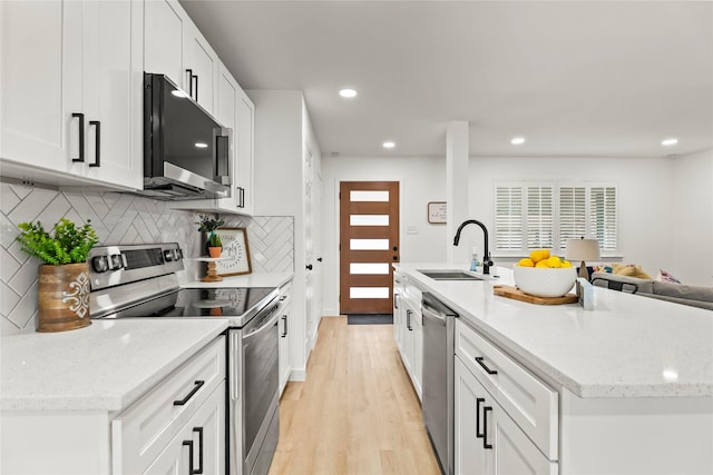 1303 Johns Dr, Euless, TX 76039 - kitchen with appliances with stainless steel finishes, a sink, decorative backsplash, recessed lighting, and a kitchen island with sink