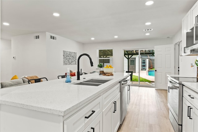 1303 Johns Dr, Euless, TX 76039 - kitchen with stainless steel appliances, a sink, recessed lighting, light wood-style floors, and a center island with sink