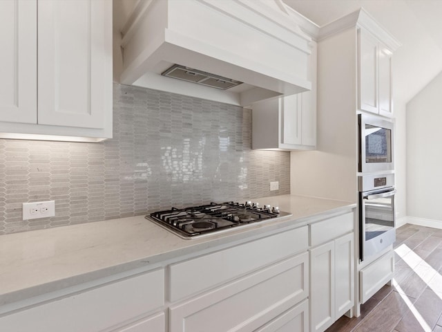 1423 Daisy Corner Dr, Celina, TX 75078 - kitchen featuring appliances with stainless steel finishes, custom range hood, decorative backsplash, white cabinetry, and light stone counters