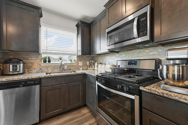 13713 Beaverhead St, Ponder, TX 76259 - kitchen featuring stainless steel appliances, a sink, dark brown cabinets, tasteful backsplash, and light stone countertops