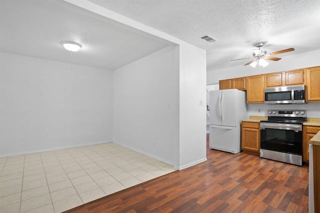736 Lee St, Mesquite, TX 75149 - kitchen with appliances with stainless steel finishes, a ceiling fan, light countertops, a textured ceiling, and dark wood-style floors