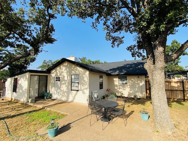 rear view of house with fence, a patio area, and a chimney