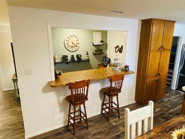 indoor bar with dark wood finished floors and baseboards