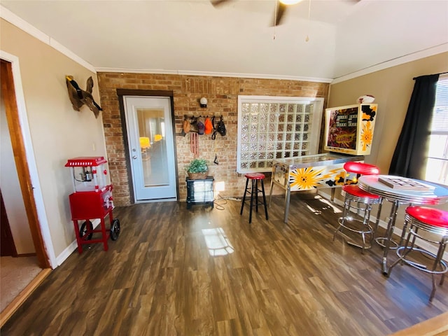 dining area with brick wall, baseboards, wood finished floors, a ceiling fan, and ornamental molding