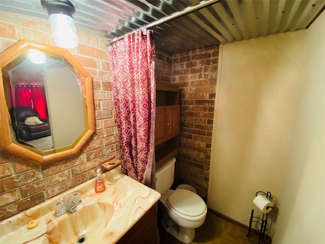 bathroom with toilet, vanity, brick wall, and a shower with shower curtain