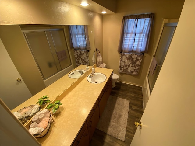 full bath featuring wood finished floors, toilet, a shower with door, vanity, and baseboards