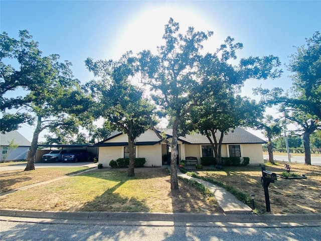 ranch-style house featuring a front lawn, an attached carport, and driveway