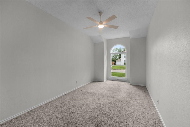 carpeted empty room with ceiling fan, a textured ceiling, baseboards, and vaulted ceiling