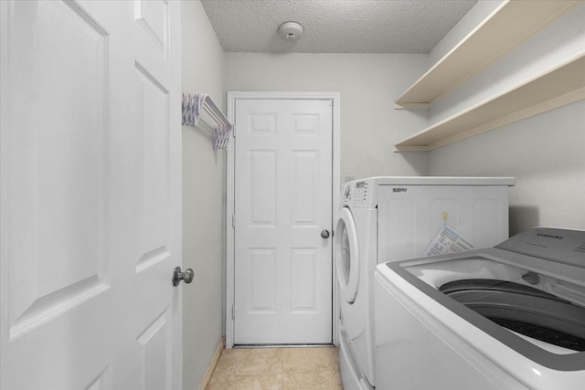 laundry area with independent washer and dryer and a textured ceiling